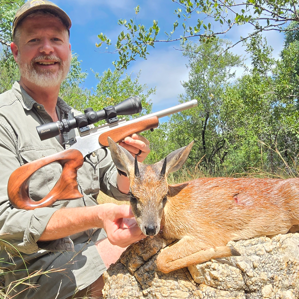 Hunter with a common duiker and a scoped rifle with a figured walnut stock