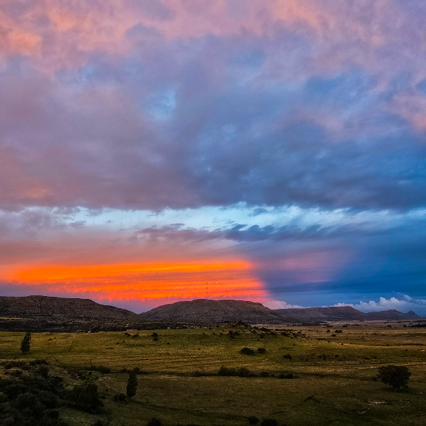 Band of orange fire under heavy cloud at sunset over Karoo hills