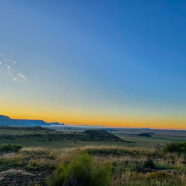Sunrise over wide plains with mist lying along a distant escarpment